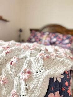 a white crocheted blanket sitting on top of a bed next to a wooden headboard