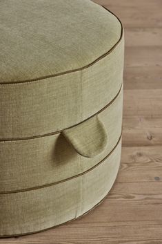 an upholstered round ottoman sits on a wooden floor