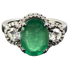 A beautiful 3.01 carat oval cut emerald ring, with 0.30 carats rose cut side stone diamonds and 0.30 carats of full cut diamond halo. The emerald center stone is transparent with a beautiful vivid green color, and all the gemstones are set in solid 18K gold with black rhodium polish, giving the ring an Art Deco look. Currently sized at US7, can be resized. We provide free shipping, and accept returns. Please feel free to message us for more information. Oval Emerald Ring With Single Cut Diamonds, Oval Emerald Ring With Rose Cut Diamonds, Classic Oval Emerald Ring With Single Cut Diamonds, Oval Emerald Ring With Rose Cut Diamonds For Anniversary, Anniversary Oval Emerald Ring With Rose Cut Diamonds, Oval Emerald Ring With Single Cut Diamonds For Anniversary, Green Oval Diamond Ring With Single Cut, Green Oval Single Cut Diamond Rings, Oval Emerald Ring With Diamond Accents