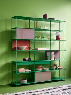 a green shelf filled with lots of books and vases on top of it's sides