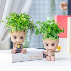 two small planters sitting on top of a white box next to each other with plants growing out of them