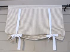 the back of a window curtain with white ribbon tied around it and hanging on a wall