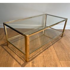 a glass and brass coffee table on wooden floor