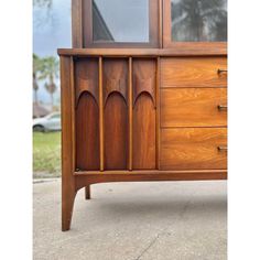 a wooden dresser with glass doors and drawers