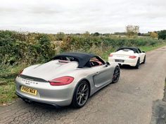 two white sports cars driving down the road