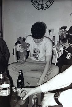 black and white photograph of two people sitting on a couch with beer bottles in front of them