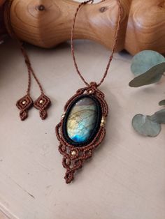 an image of a necklace with a stone in it on a wooden table next to some plants