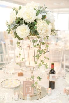 a vase filled with white flowers sitting on top of a table next to a bottle of wine