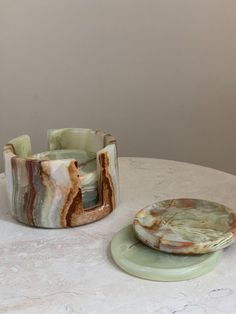 two pieces of pottery sitting on top of a white marbled table next to each other