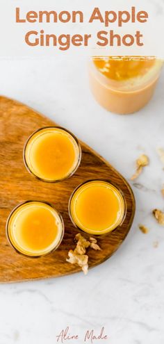 three glasses filled with orange juice sitting on top of a wooden cutting board