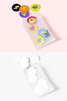 three different colored buttons in a package on a pink and white background, one with the number