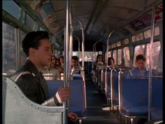 a man sitting on a bus holding onto the seat and looking at something in front of him