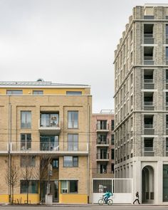 two tall buildings next to each other on a street with a person riding a bike