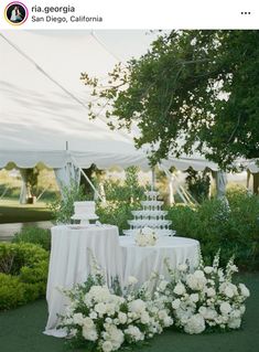 a table with white flowers and cake on it in front of a tented area