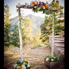 an outdoor ceremony setup with flowers and greenery on the altar, in front of mountains