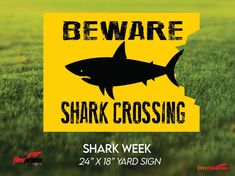 a shark crossing sign is shown in the grass