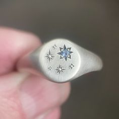 This blue Montana sapphire star signet ring in sterling silver has hand engraved stars which will vary slightly with each ring. If you'd like this design customized for you or need a rush order, contact me. DETAILS - hand engraved star/bead setting - 2 mm medium light blue Montana sapphire - ring measures 9 mm on top, tapers to 3 mm in back. - soft satin and oxidized finish emphasizes star details - hand engraved star pattern will vary slightly with each ring - made to order within 3-5 days IMPORTANT: Please be aware that delivery times are estimates and USPS may experience delays. Please be sure to look at estimated ship dates on made to order items and contact me if you need your order to arrive by a specific date.   Follow me on Instagram (ebethscottdesigns) and Facebook (Elizabeth Scot Elizabeth Scott, Space Rings, Montana Sapphire Ring, Paper Ring, Signet Rings, Medieval Jewelry, Silver Signet Ring, Plastic Ring, Montana Sapphire