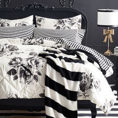 a black and white bedroom with striped bedding, two nightstands and a lamp