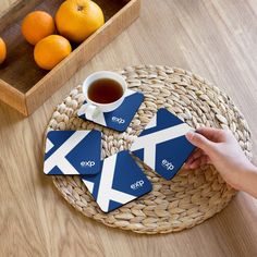 a person is holding up two coasters with the flag of scotland and an orange