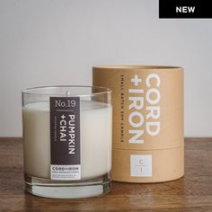 a candle sitting on top of a wooden table next to a cardboard box and container