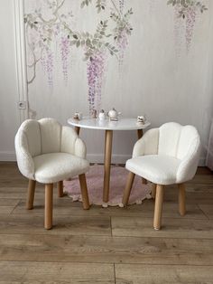 two chairs and a table in front of a wall with flowers painted on the walls