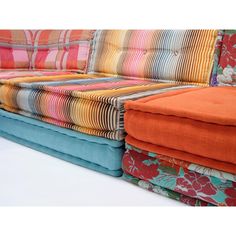 a multicolored couch is stacked on top of each other with colorful fabrics covering it