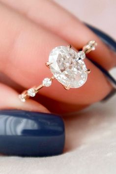 a woman's hand holding a ring with an oval shaped diamond in the middle