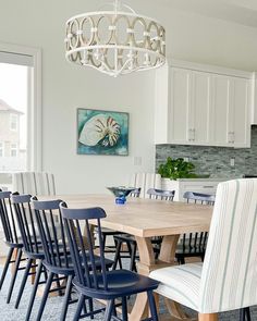 a dining room table with chairs and a chandelier hanging from it's ceiling