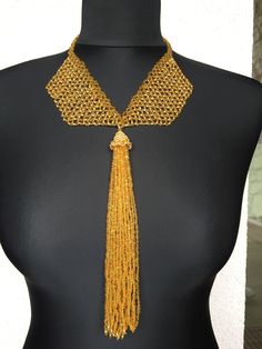 This unique gold tassel pendant necklace is a unique and luxurious piece of jewelry for any special occasion. It is made entirely of Czech beads, and in the hat of the tassel I have swapped several Swarovski crystals. The buckle is made is from the same beads . This is the perfect gift for yourself or a loved one who values uniqueness and class. Elegant Gold Bead Necklaces For Party, Elegant Gold-plated Beaded Necklaces, Elegant Gold Beaded Necklaces For Parties, Elegant Party Beaded Necklaces With Gold Beads, Elegant Party Gold Beaded Necklaces, Elegant Gold Beaded Necklaces For Gifts, Handmade Elegant Long Chain Necklace, Elegant Gold Beaded Chain Necklace For Party, Luxury Gold Beaded Necklace For Party