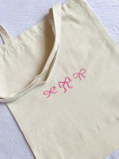 a white bag with pink embroidered letters on it