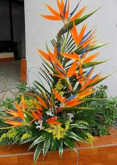 an arrangement of tropical flowers in a wooden planter