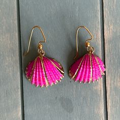 two pink seashells are hanging from gold ear wires