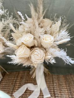 a bridal bouquet with white flowers and feathers on a tableclothed cloth background