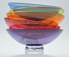 a stack of colorful bowls sitting on top of each other in front of a white background