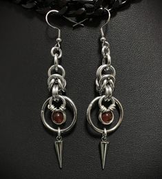 These earrings were inspired by Vlad the Impaler - made with chainmail rings, spikes and carnelian stones Earring hooks are Stainless steel  Earrings measure at approximately 3.25 inches long and approximately .75 inches wide They are hand made and sizes may vary depending on hook type Handmade in the US Chainmail Ring, Chainmaille Jewelry Patterns, Unisex Earrings, Bone Earrings, Carnelian Crystal, Chainmail Jewelry, Chain Maille Jewelry, Chain Mail, Unisex Gifts