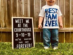 a little boy standing next to a sign that says best fam ever