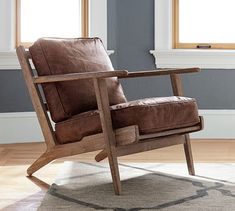 a brown leather chair sitting on top of a wooden floor next to a white rug