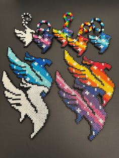 several pieces of art made out of perler beads on a black surface with white and blue designs