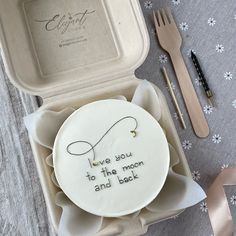 a cake with writing on it sitting in a box next to utensils and a fork