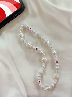 a cell phone with a white beaded necklace next to it