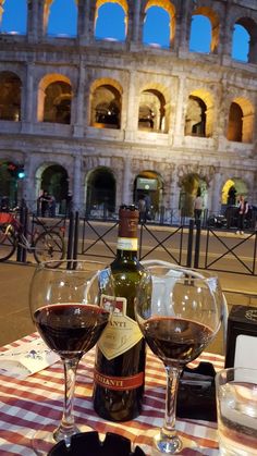 two glasses of wine sitting on top of a checkered table cloth with an arch in the background