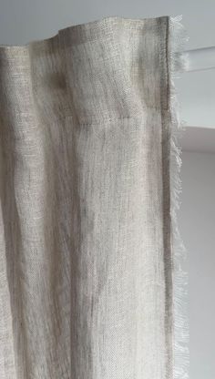 a white curtain hanging from the side of a window with fringed fabric on it