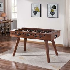 a foosball table in a living room with two pictures on the wall behind it