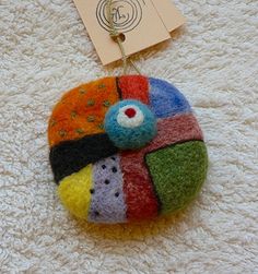 a multicolored rock hanging from a hook on a white carpet with a tag attached to it