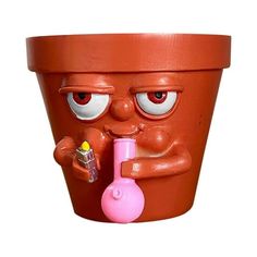 a clay pot with a face holding a bottle and a beaker in it's mouth