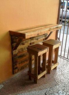 three wooden stools sitting next to each other in front of a wall with a bench on it