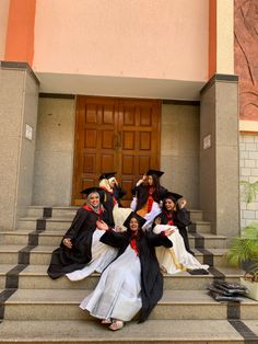 four graduates sitting on steps in front of a building