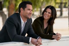 a man and woman sitting next to each other at a table smiling for the camera