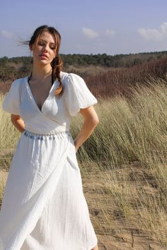 Made from 100% Organic Cotton, the Perla dress is the epitome of romance. With a timeless, bohemian style, this dress features a wrap-around body, short puff sleeves and a relaxed fit that is perfect for any occasion.  Colour: Optic White Size: Model is 6-8 wearing S (sizes come up fairly small)  Fabric: 100% Organic Cotton Elegant V-neck Puff Sleeve Beach Dress, Chic Flowy Wrap Dress With Short Sleeves, Feminine Midi Dress With Surplice Neckline For Beach, Feminine Surplice Neckline Midi Dress For Beach, Summer Brunch Wrap Dress With Short Sleeves, Bohemian Flowy Wrap Dress With Surplice Neckline, Bohemian Surplice Neckline Wrap Dress For Brunch, Bohemian Wrap Dress With Surplice Neckline For Brunch, Chic Short Sleeve Wrap Dress For Beach