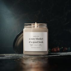 a cozy blanket and a good book candle sitting on a table in front of a dark background